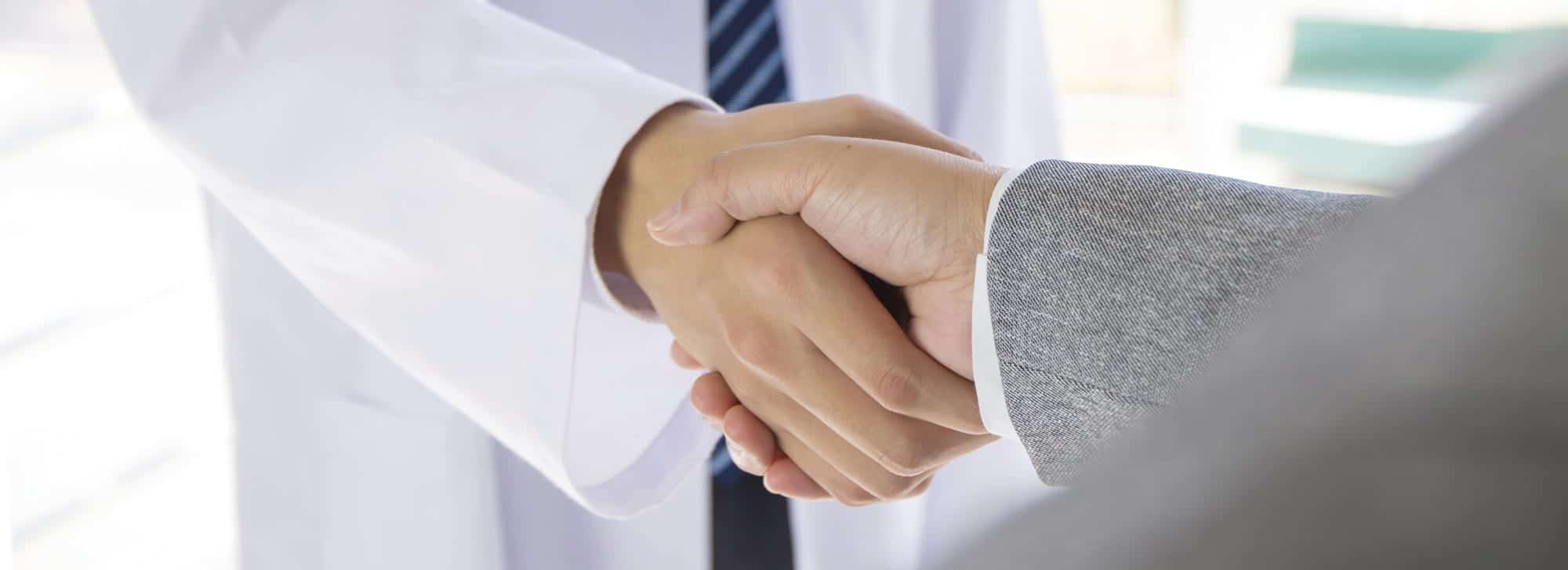 Medical professional and sales representative shaking hands